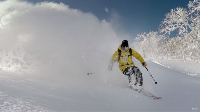 Skier in yellow jacket skiing down a snowy mountain in Japan