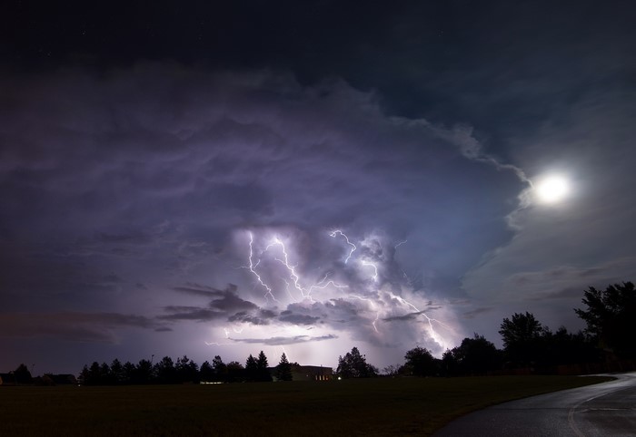 Lightning storm over a field at night with moon