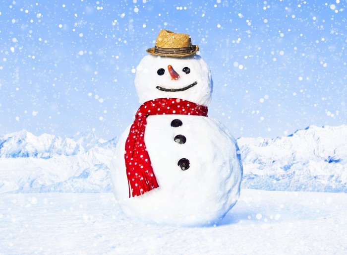 Snowman with hat and scarf in snowy mountains