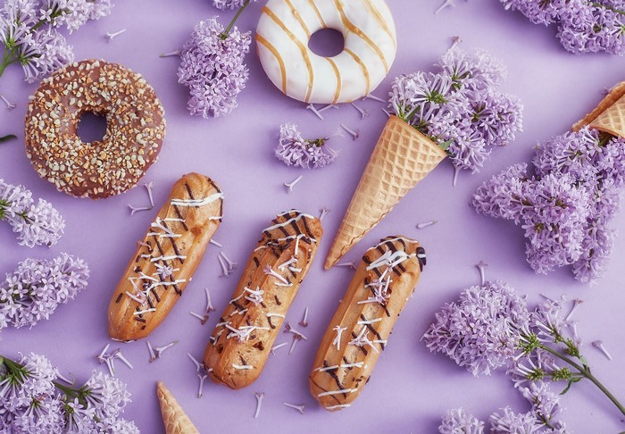 Desserts and lilac flowers on a purple background