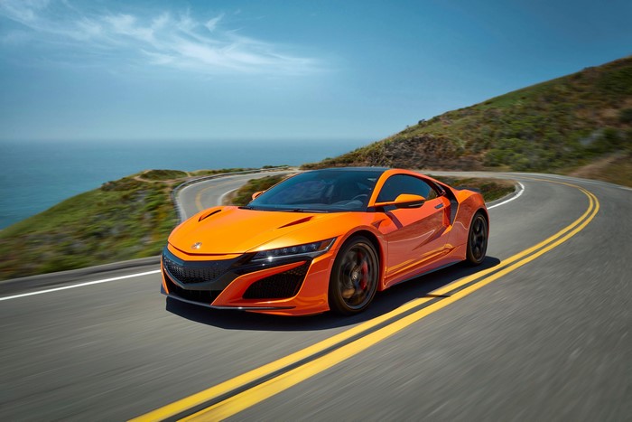 Orange Acura NSX driving on a coastal road
