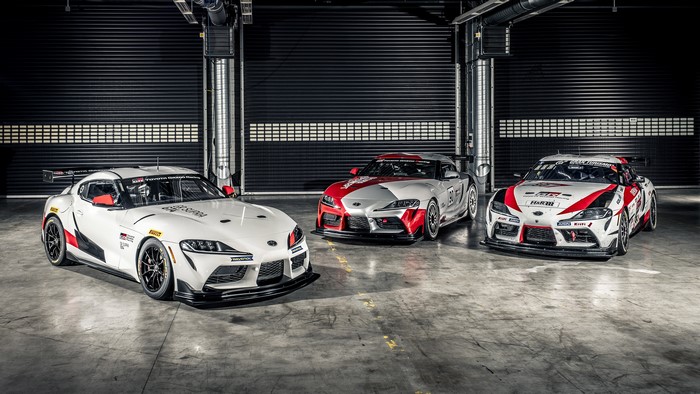 Three Toyota GR Supra race cars in a garage