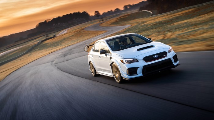 White Subaru WRX STI on a race track at sunset