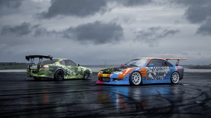 Two Nissan drift cars on a wet track