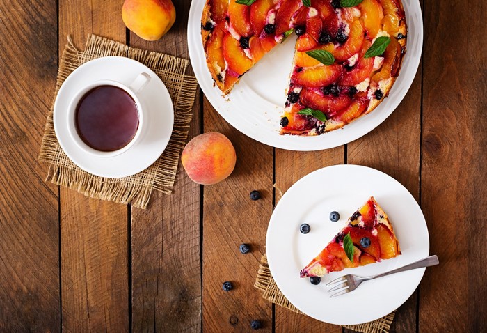 Peach and blueberry cake with coffee on a wooden table