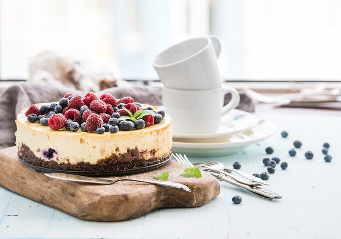 Cheesecake with raspberries and blueberries on a cutting board