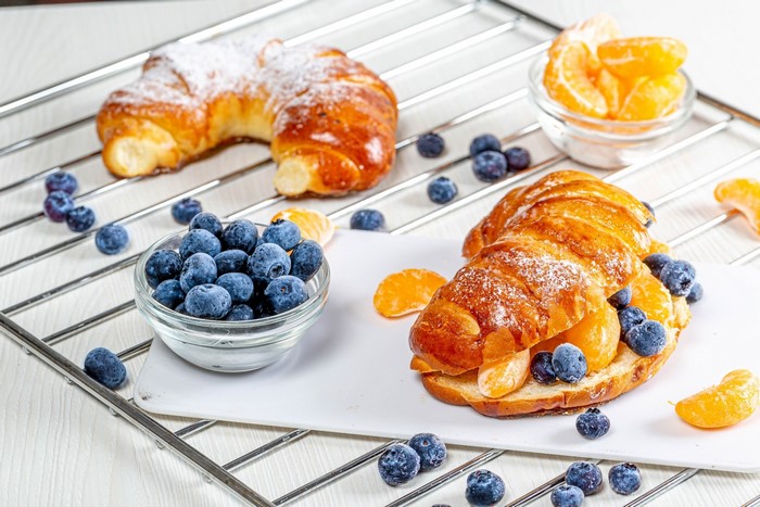 Croissants with blueberries and tangerines on a cooling rack