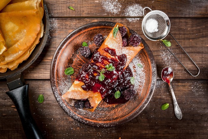 Crepes with blackberries and jam on a plate