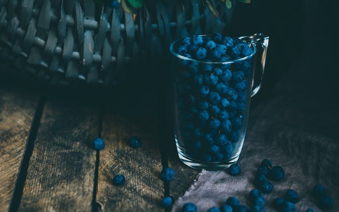 Blueberries in a glass pitcher on a wooden table