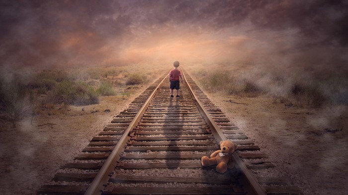 Child and teddy bear on train tracks