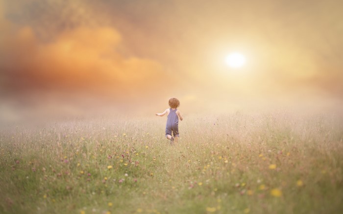 Child running in a field at sunset