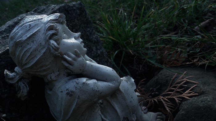Stone statue of a child in grass