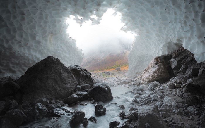 Ice cave with stream and rocky landscape