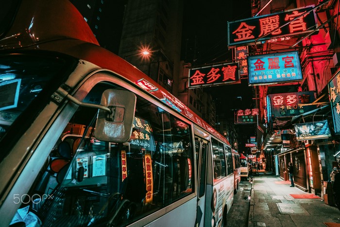 Hong Kong street with buses and neon signs at night