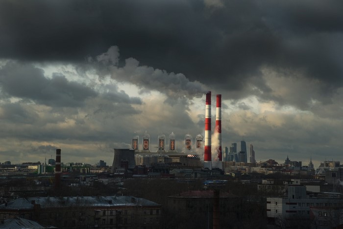 Industrial chimneys and city skyline under stormy clouds