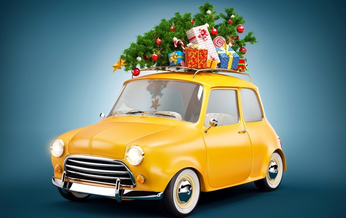 Yellow car with Christmas tree and gifts on roof