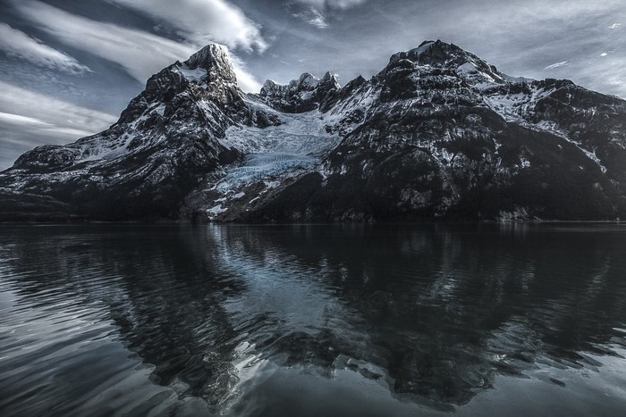 Snow-capped mountains reflected in a dark lake