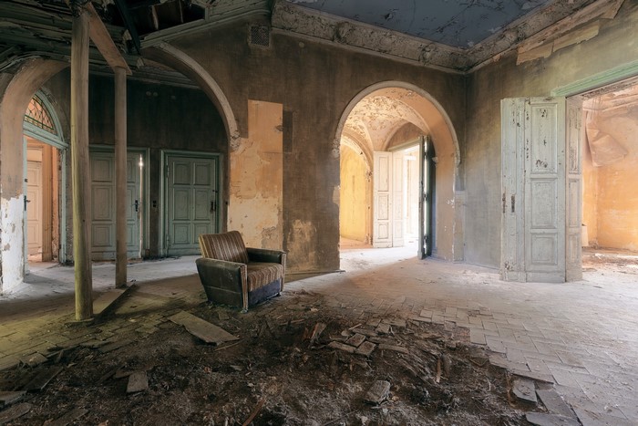 Abandoned room with armchair and arched doorways