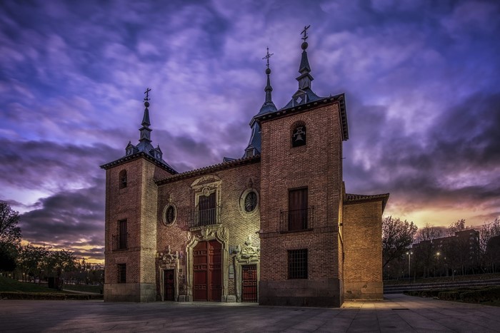 Brick church with spires against a dramatic purple sky