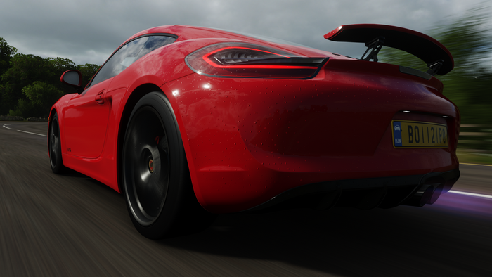Red Porsche Cayman GTS driving on a wet road