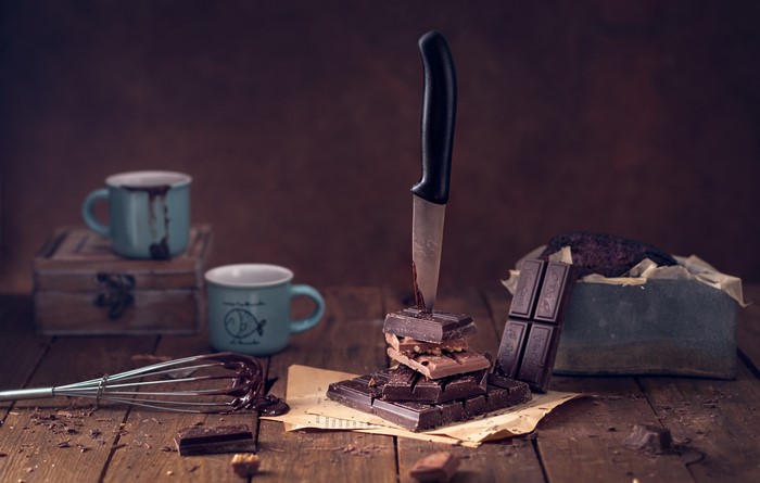 Chocolate bars, knife, and mugs on a wooden surface