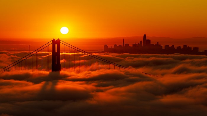 Golden Gate Bridge and San Francisco cityscape at sunset above clouds