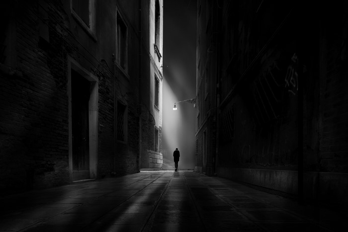Man walking down a dark alleyway in Venice