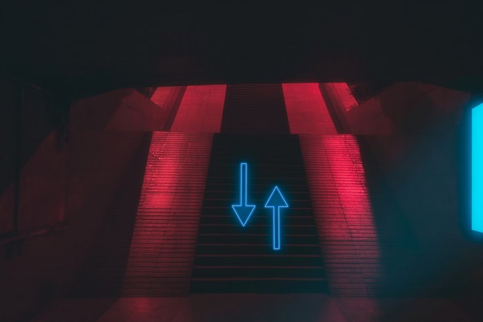 Neon arrows on red lit stairs