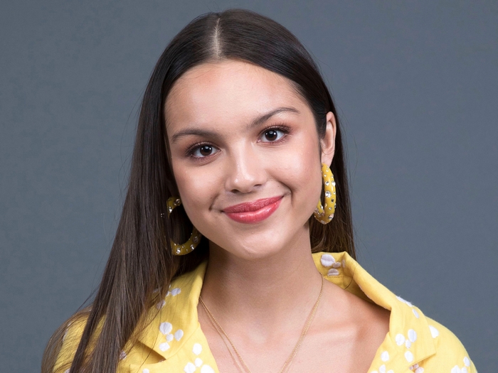 Olivia Rodrigo smiling, wearing a yellow shirt