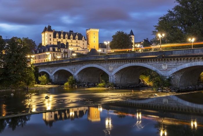 Bridge over river with castle and reflections at dusk