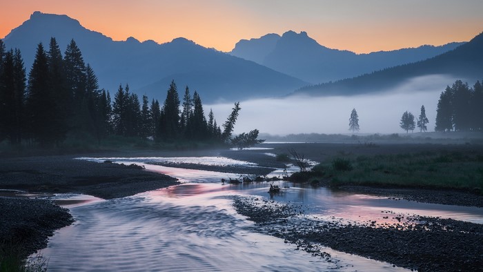 Misty river valley at sunrise with mountains
