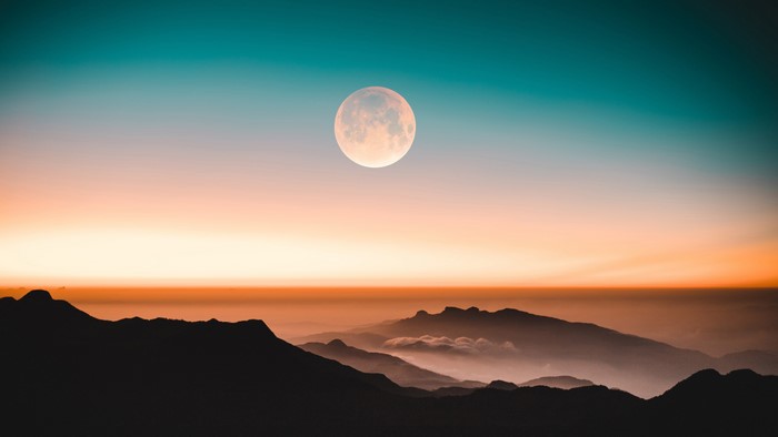 Moon over misty mountains at sunset