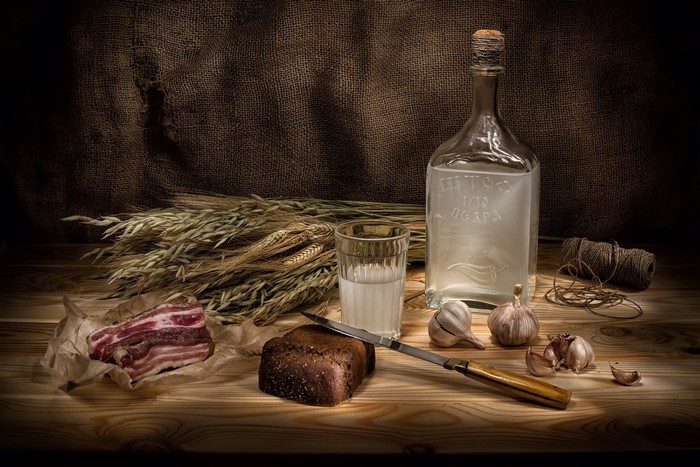 Still life with vodka, bacon, bread, wheat, and garlic