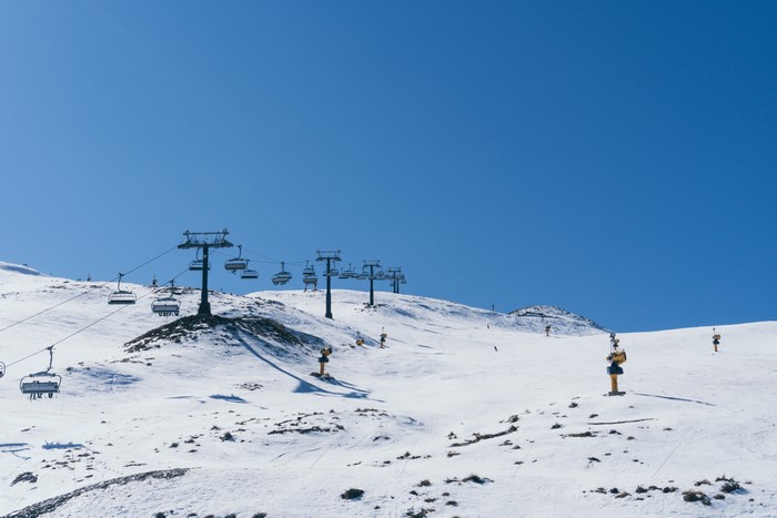 Ski resort with chairlifts on snowy mountains under blue sky