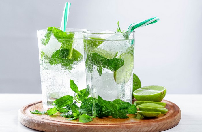 Two mojitos with mint and lime on a wooden board