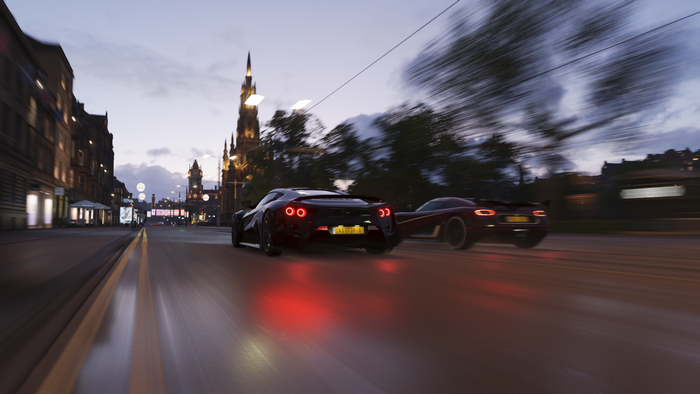 Two sports cars racing on a city street at dusk in Forza Horizon 4