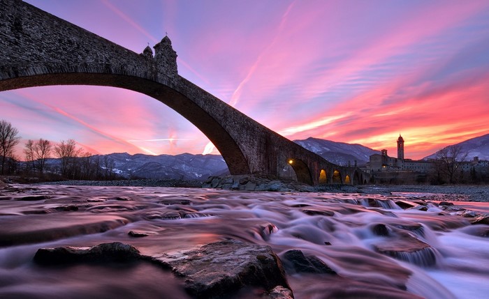Stone bridge over a river at sunset in Italy
