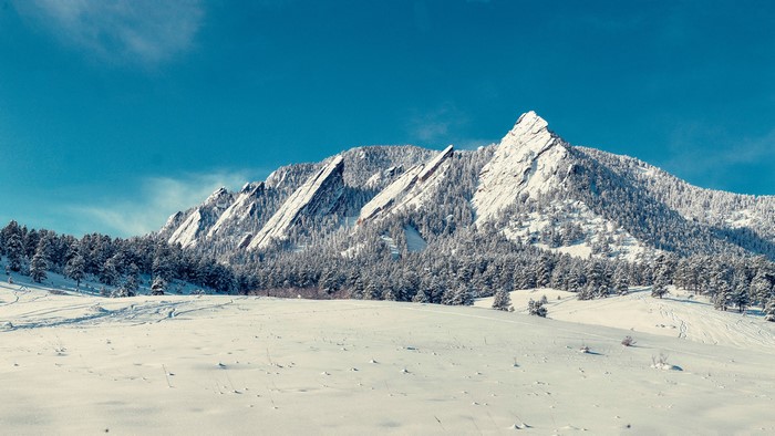 Flatirons mountains covered in snow under a blue sky