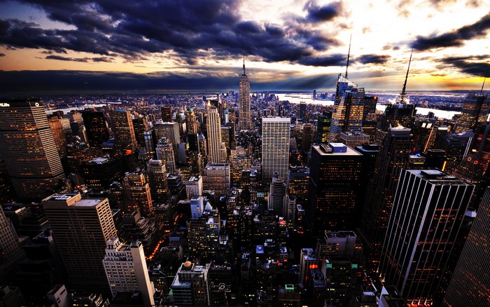 New York City cityscape at dusk with dramatic clouds