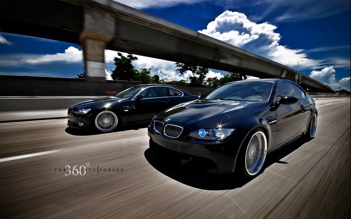 Two black BMW E92 cars on a highway