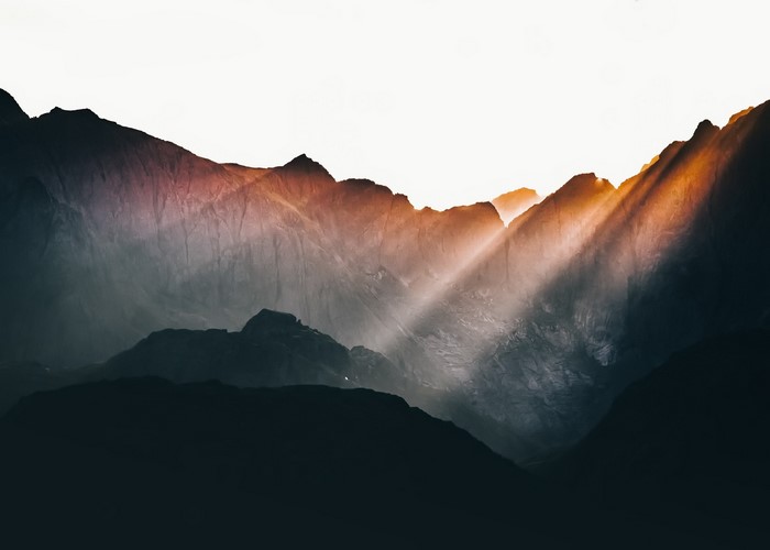 Sun rays piercing through dark mountains