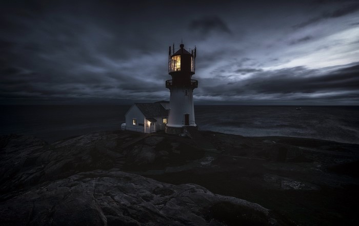 Lighthouse on a rocky shore at night