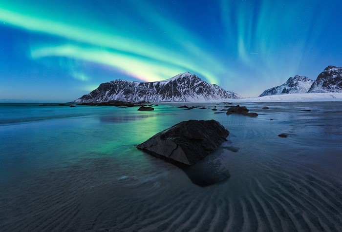 Aurora Borealis over snowy mountains and beach