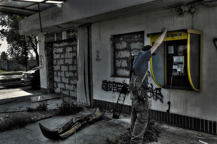Man using a payphone in an abandoned gas station