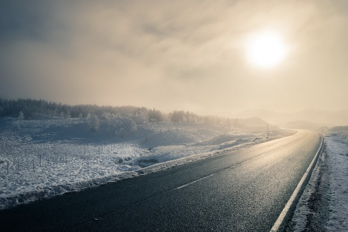 Winding asphalt road through a snowy winter landscape in Scotland