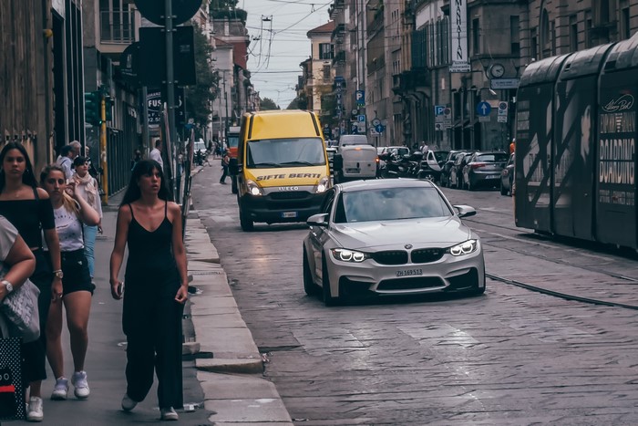 BMW M3 on a street in Milano, Italy with people and tram