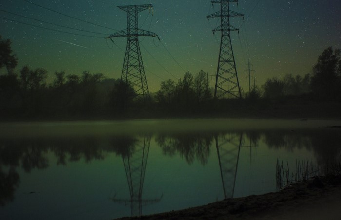 Power lines over a lake at night with stars