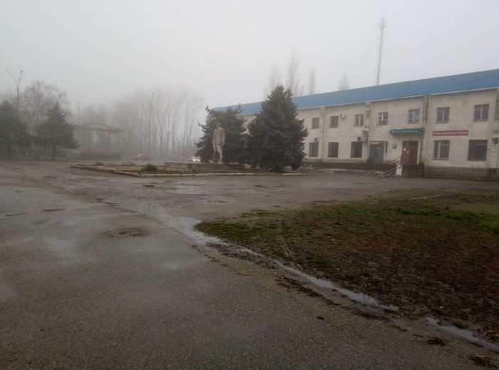 Statue in a foggy town square with a building