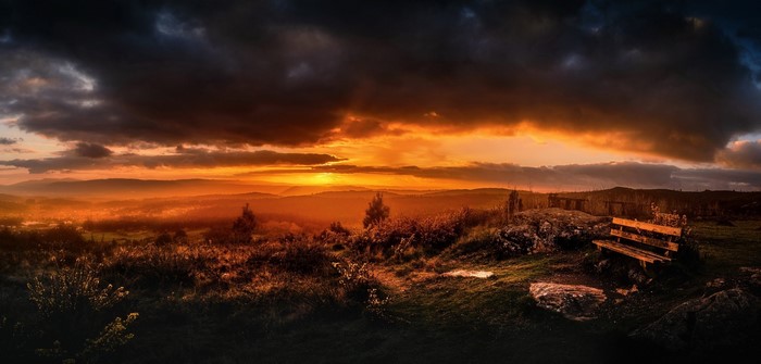 Sunset over rolling hills with a wooden bench