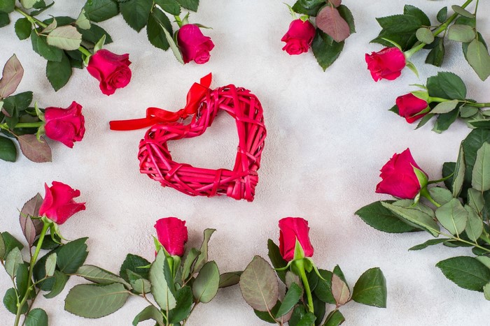 Red roses and heart decoration on a textured surface